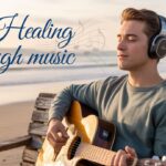 Person Playing Guitar on the Beach With Headphones
